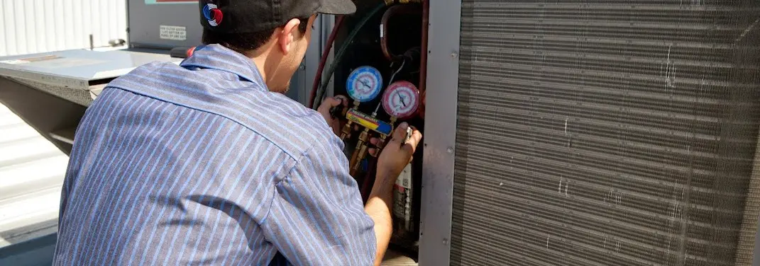 HVAC technician servicing a condenser unit in Oak Ridge
